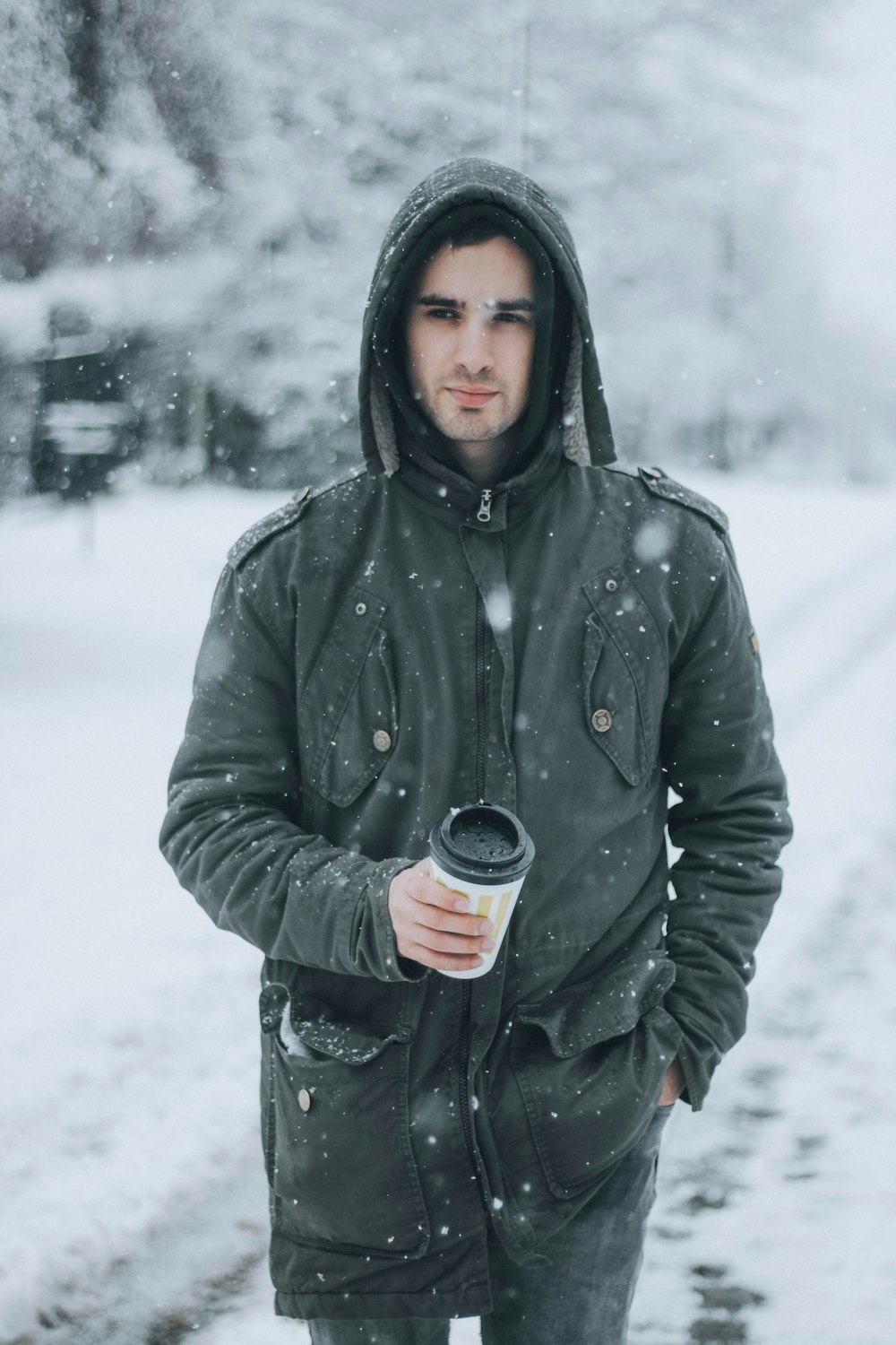 a man standing in the snow holding a cup of coffee