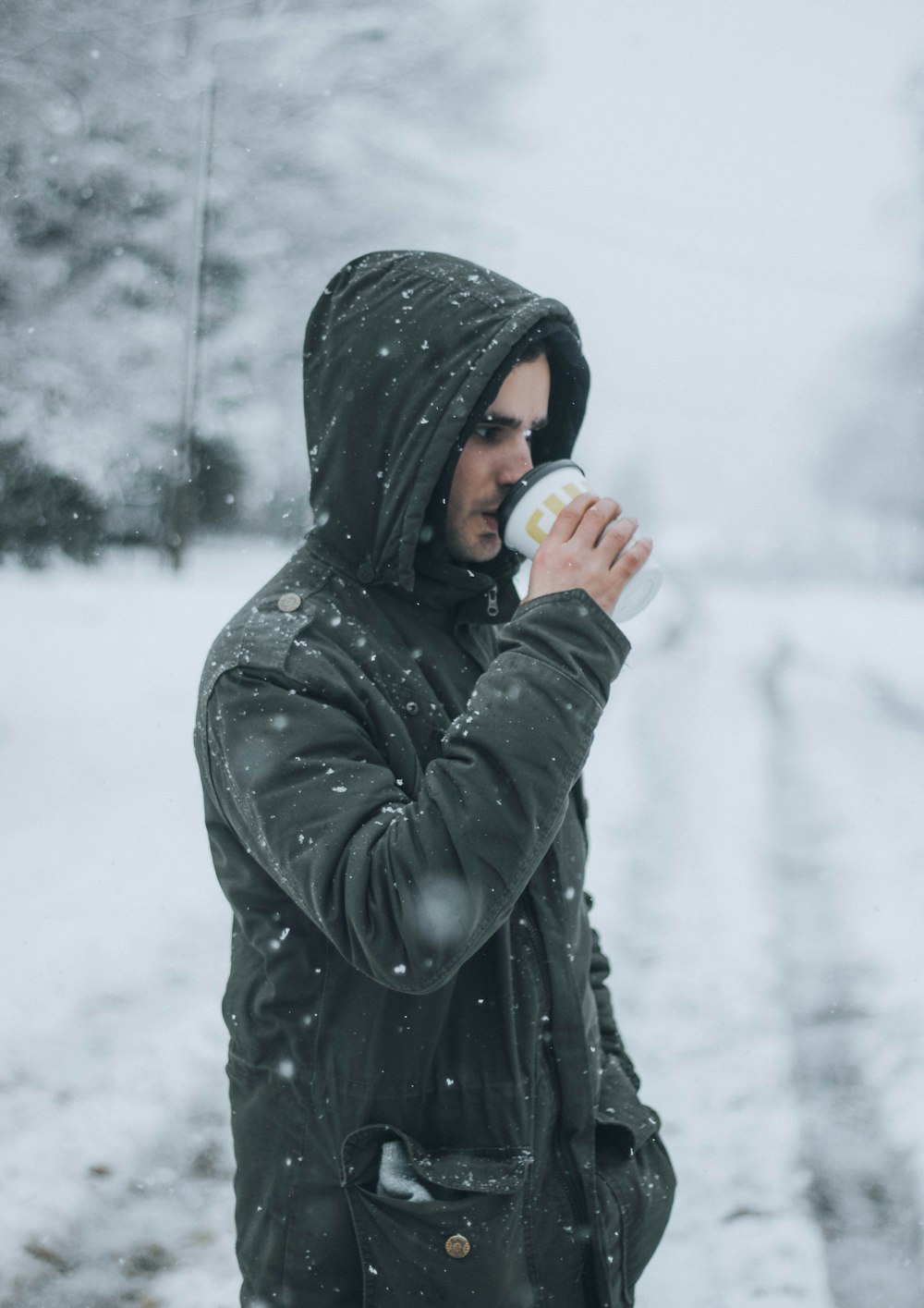 a man standing in the snow drinking from a cup