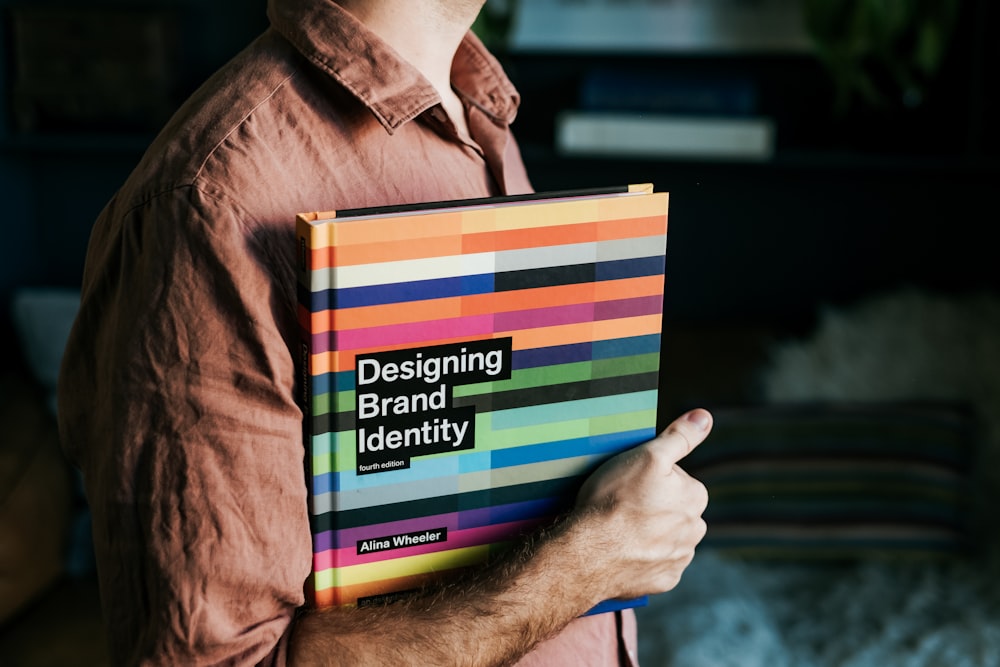 a man holding a book that says designing brand identity