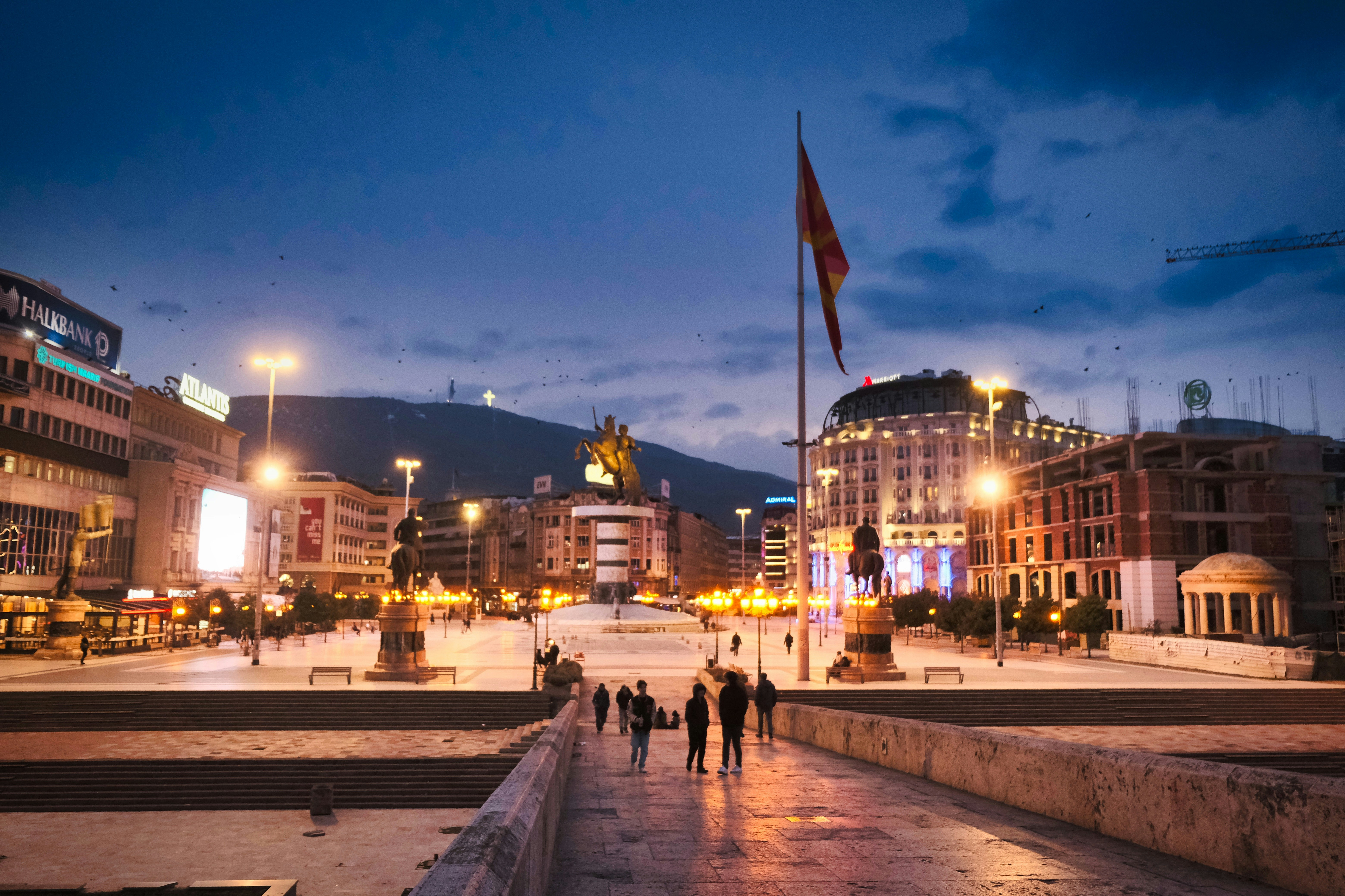 a group of people walking down a street next to tall buildings