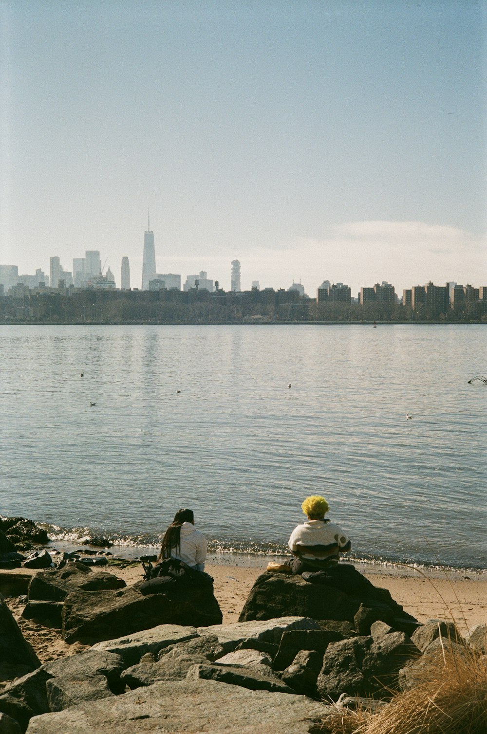 two people sitting on rocks near the water