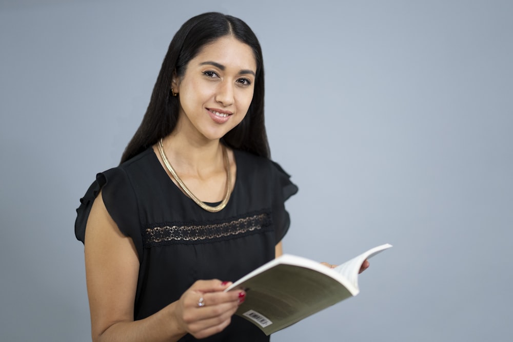 a woman in a black dress holding a book