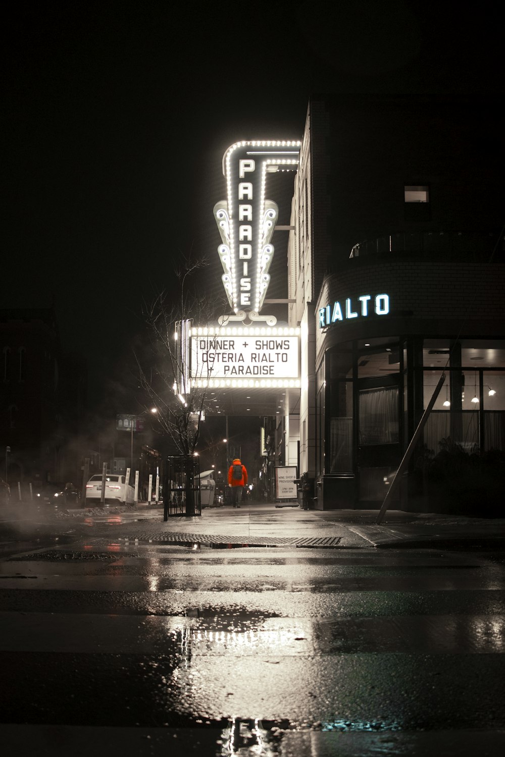 a wet city street at night with a neon sign
