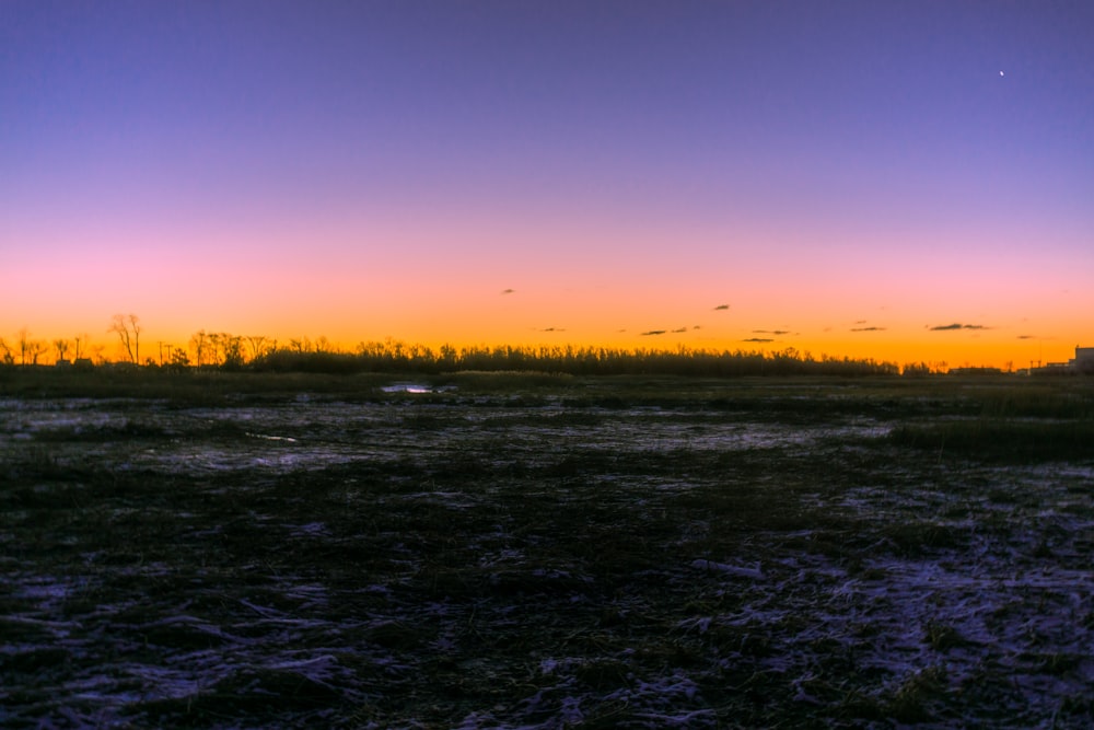 the sun is setting over a grassy field