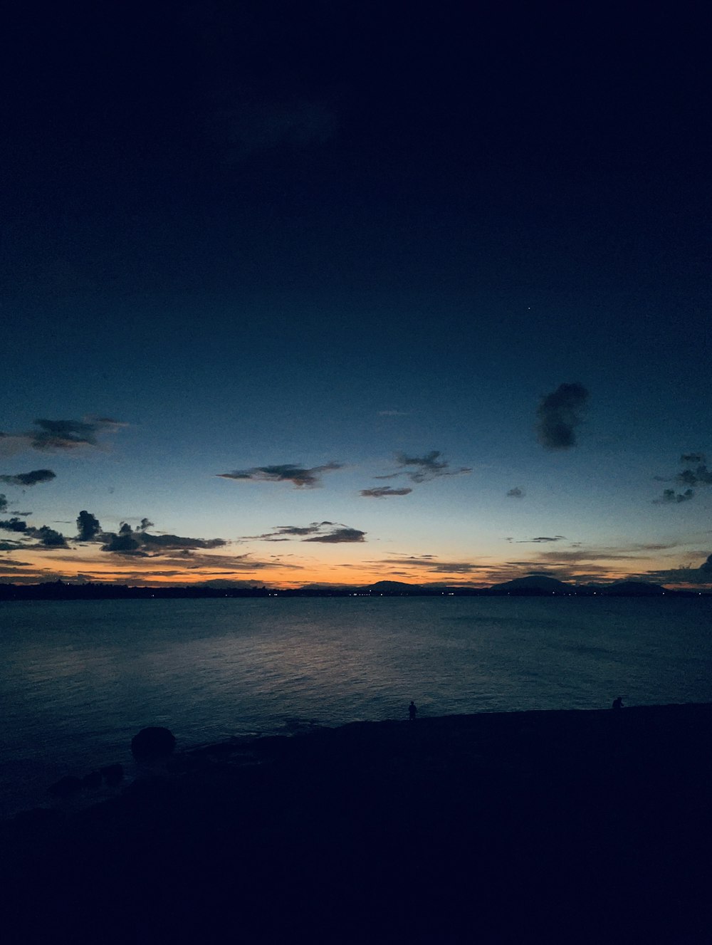 the sun is setting over the ocean with clouds in the sky