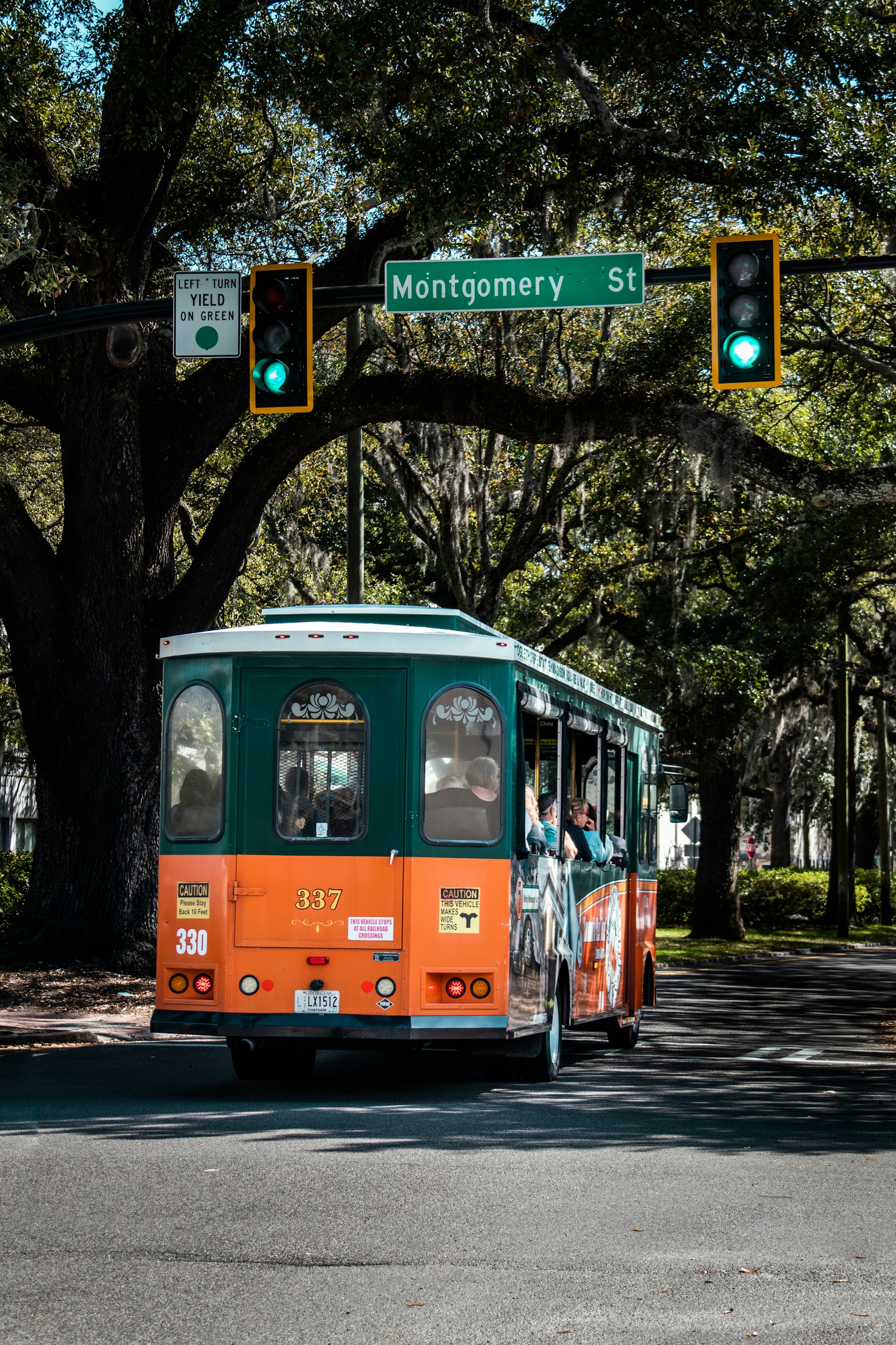 an orange and green trolley driving down a street