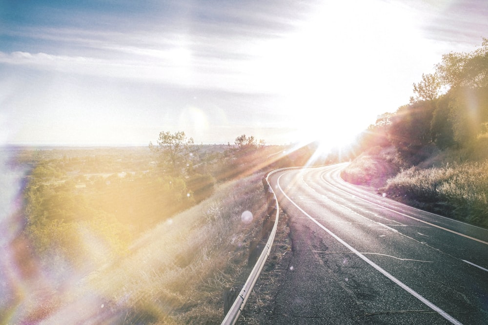 the sun shines brightly over a road in a rural area