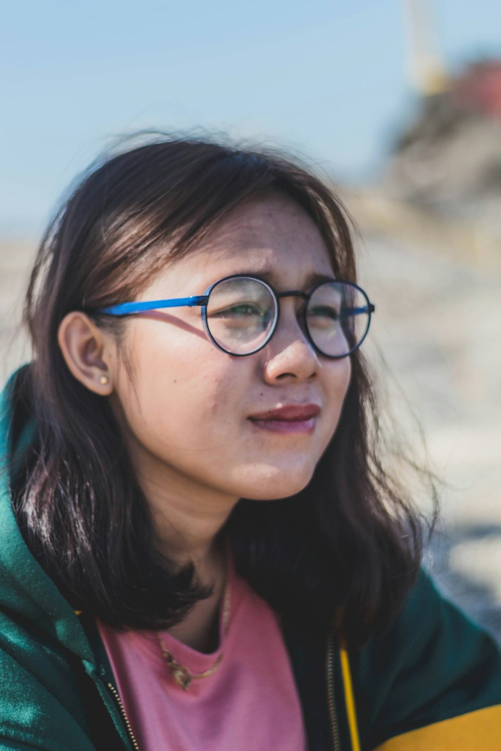 a woman wearing glasses and a green jacket