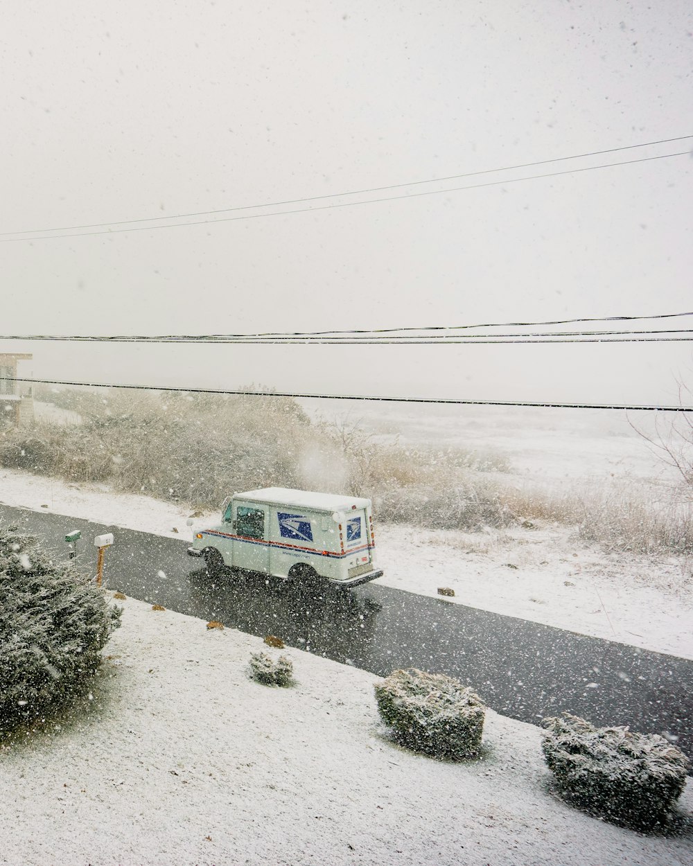 a white truck driving down a snow covered road