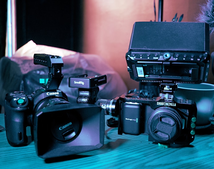 a couple of cameras sitting on top of a wooden table