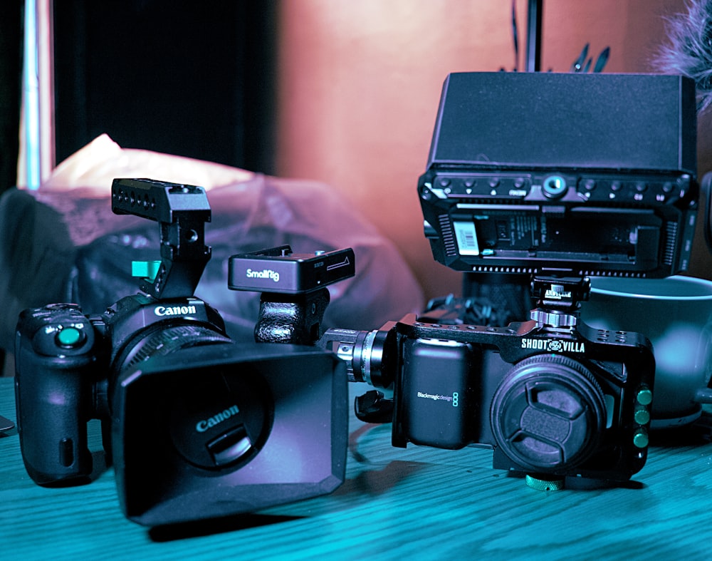 a couple of cameras sitting on top of a wooden table