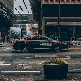 A sleek black-and-white police cruiser parked on a city street at dusk.