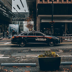 A sleek black-and-white police cruiser parked on a city street at dusk.