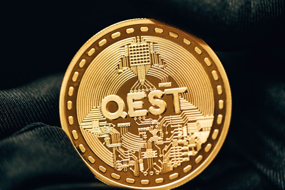a gold coin with the word qest printed on it