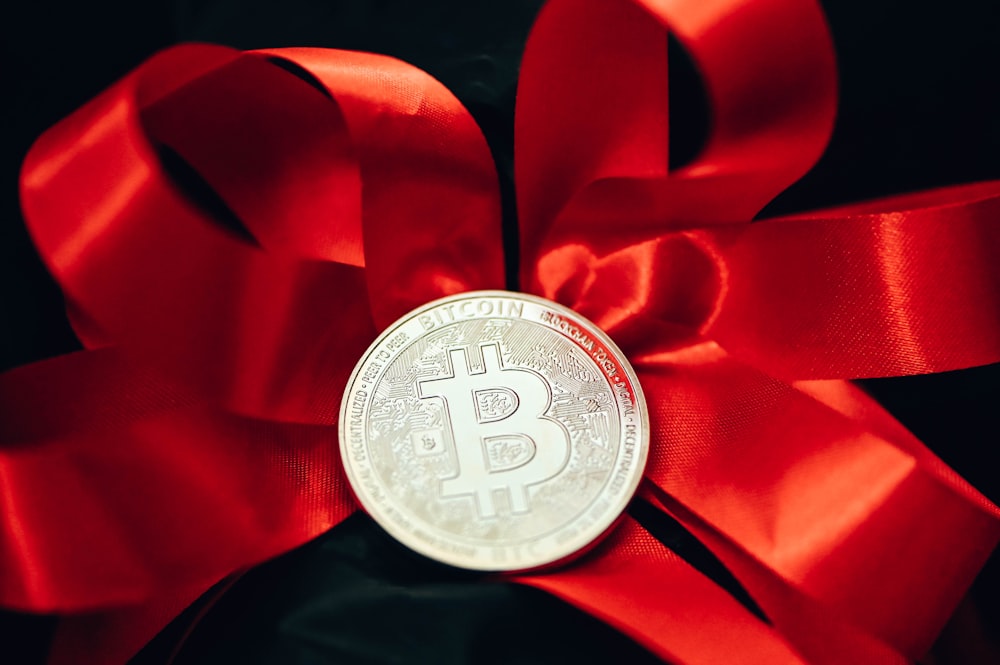 a bitcoin tied to a red ribbon