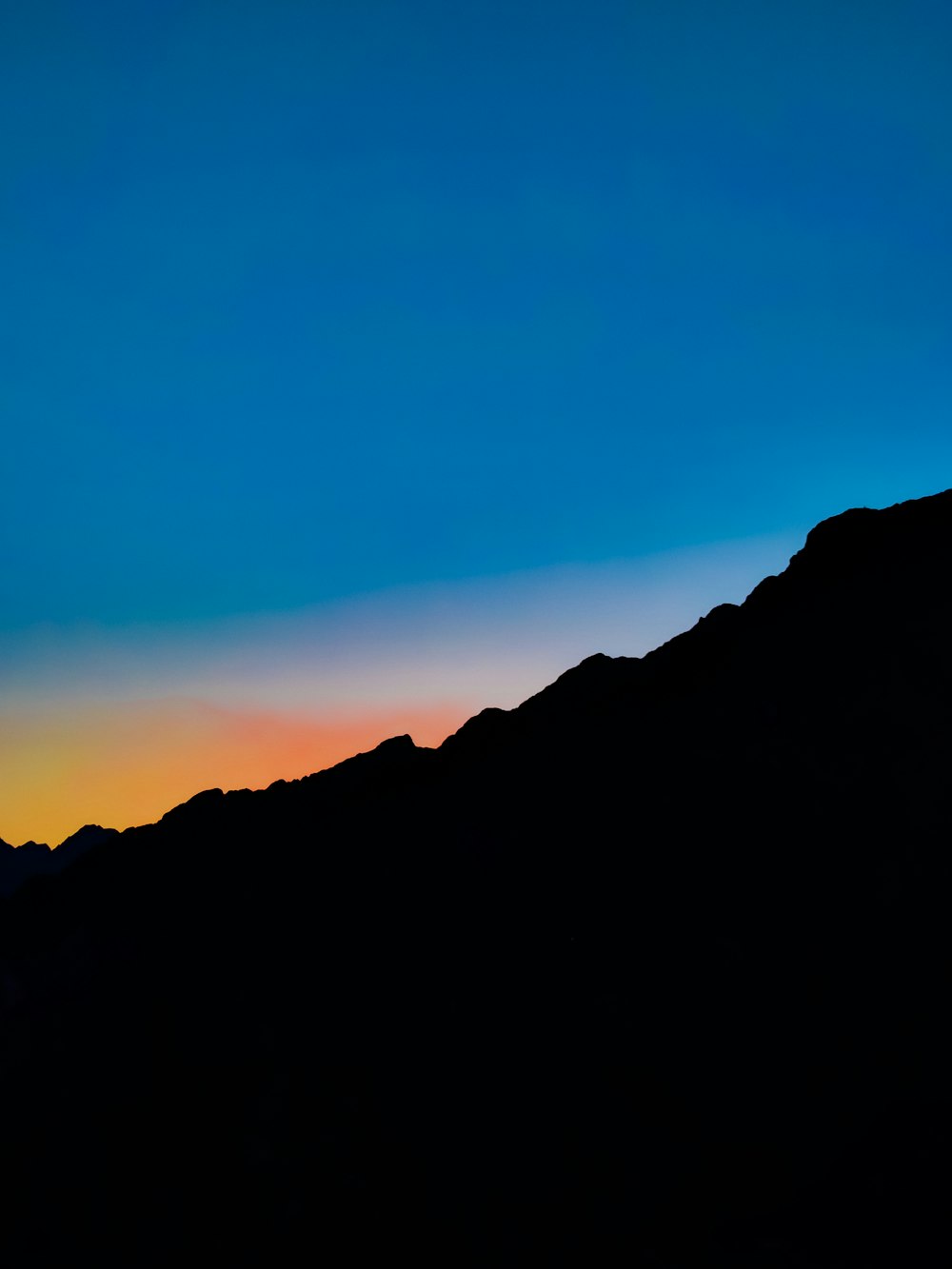 una silueta de una persona parada en la cima de una montaña