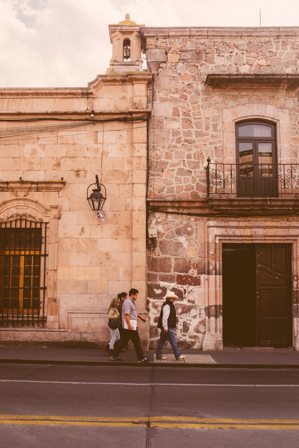 a group of people walking down a street next to a tall building