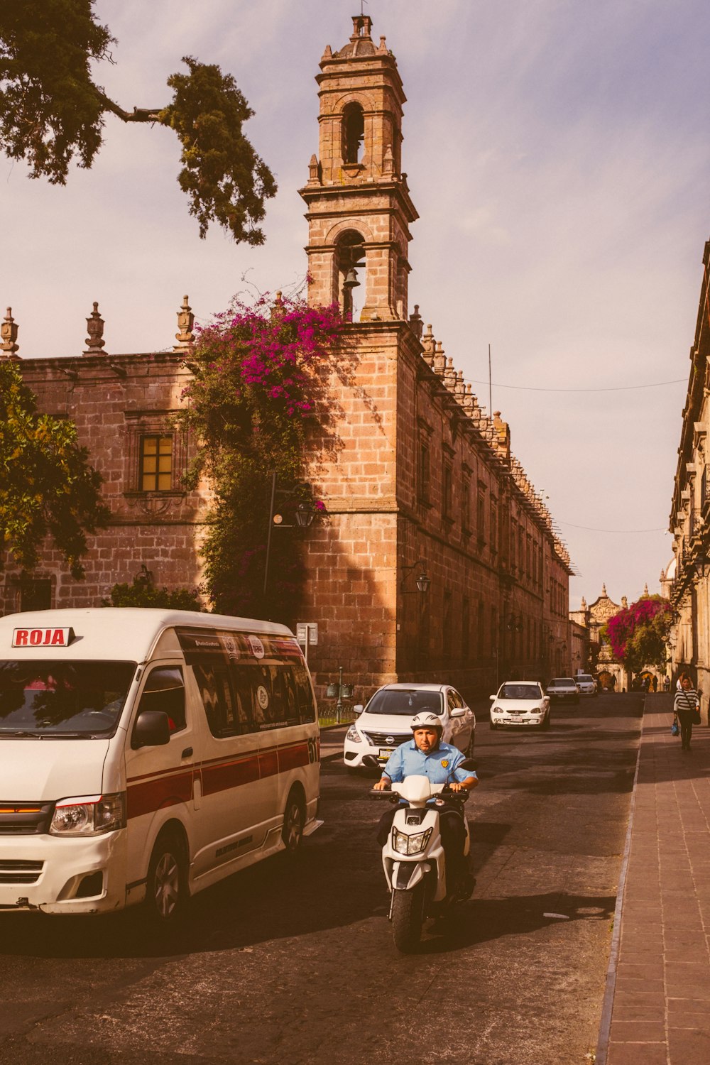 a man riding a motorcycle down a street next to a tall building