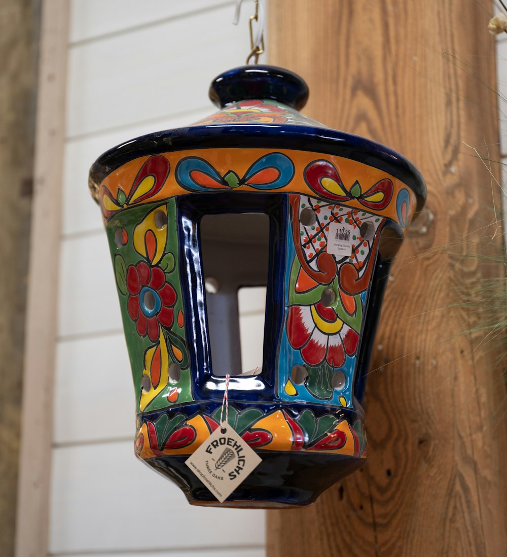 a colorful bird feeder hanging from a wooden post