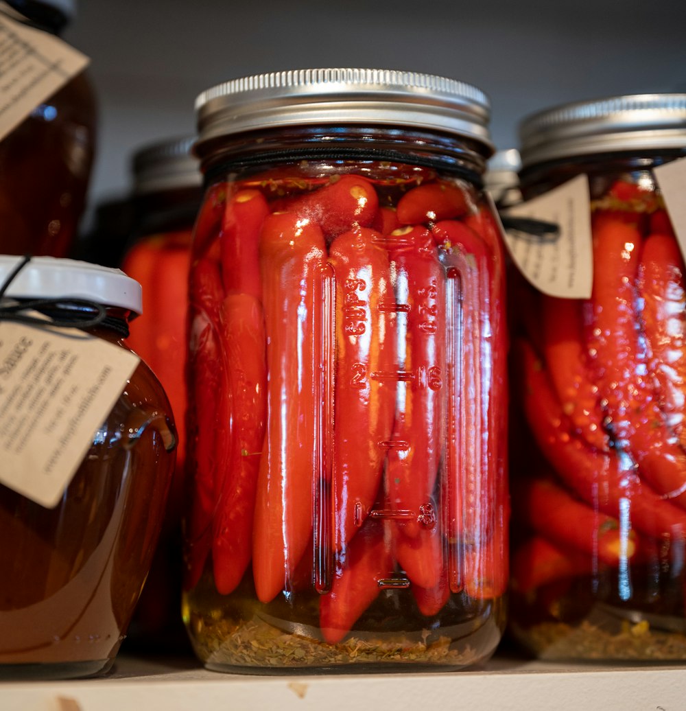 several jars of pickled red peppers on a shelf