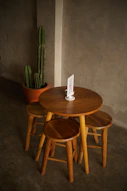 a wooden table with three stools and a cactus