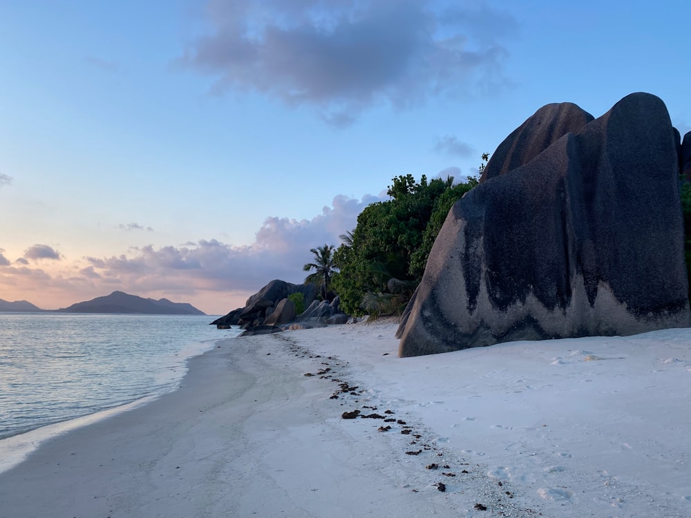 a sandy beach with a rock formation next to the ocean