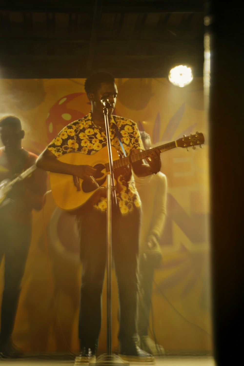 a man standing in front of a microphone while holding a guitar