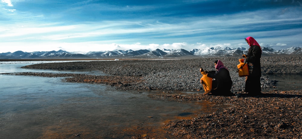 a group of people standing next to a body of water