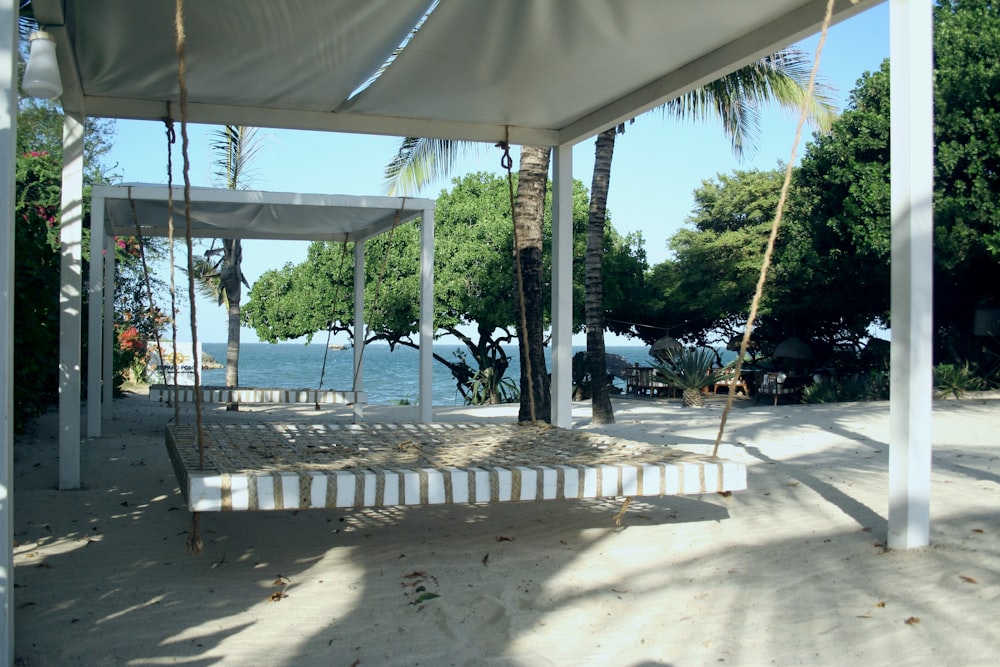 un letto bianco seduto sulla cima di una spiaggia sabbiosa