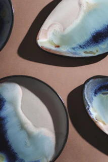 Close-up of elegant ceramic plates with subtle glaze variations arranged on a rustic wooden table.
