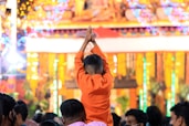 a man in an orange outfit standing in front of a crowd of people