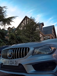A sleek metallic grey car parked in front of a modern Bavarian dealership building under a clear sky.