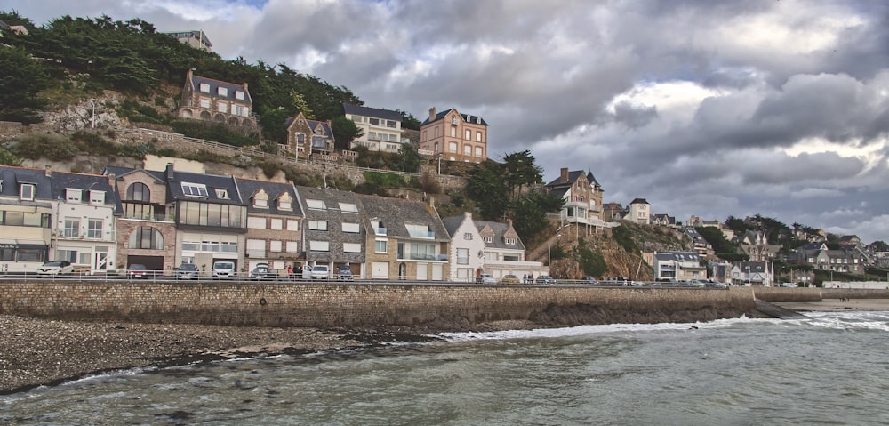 a row of houses on a hill next to a body of water