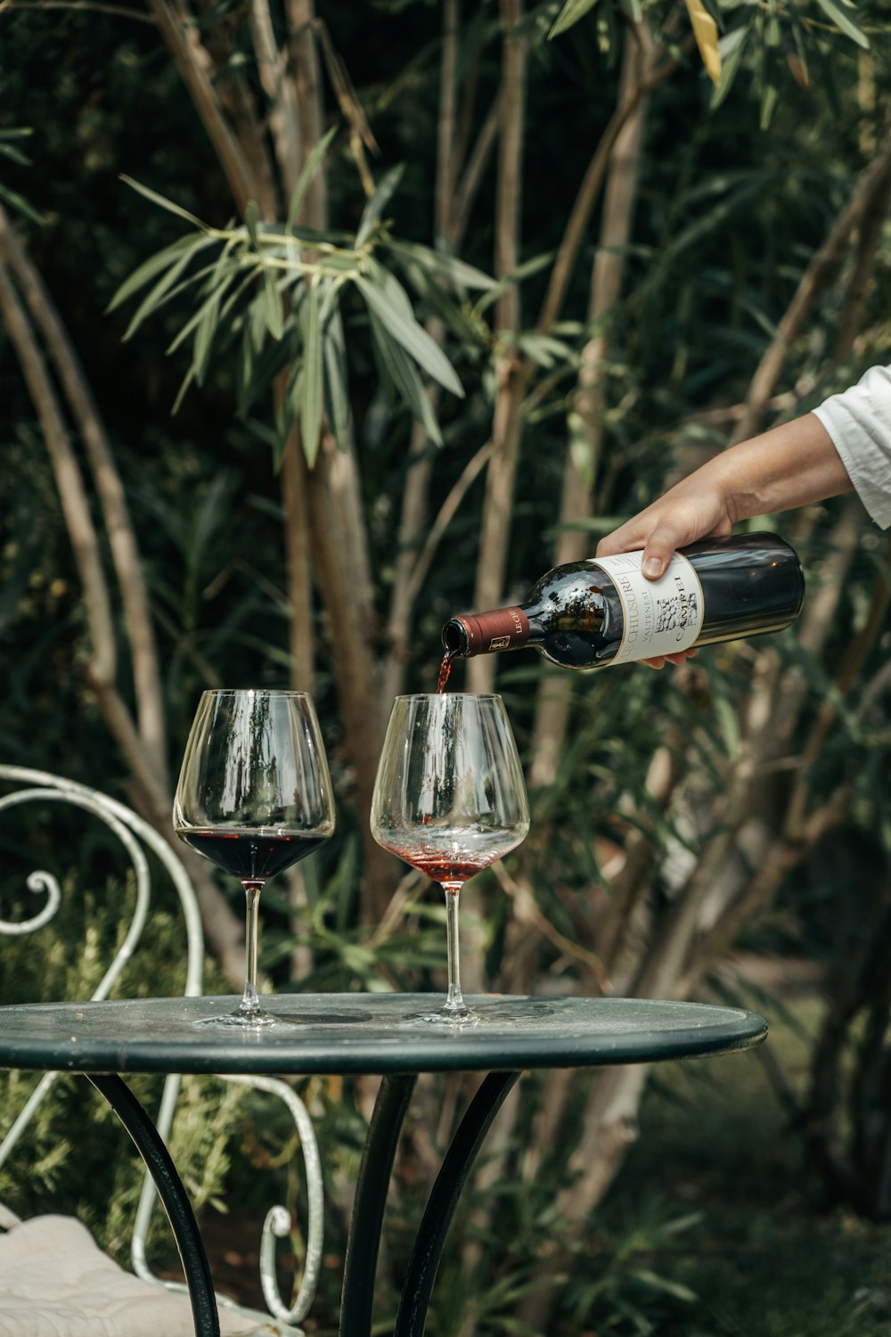 a person pouring a glass of red wine