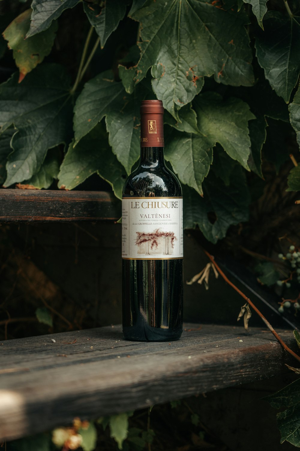 a bottle of wine sitting on top of a wooden bench