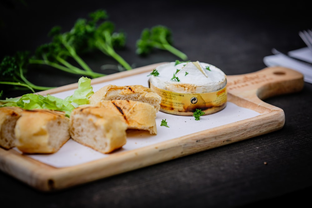 a wooden cutting board topped with bread and vegetables