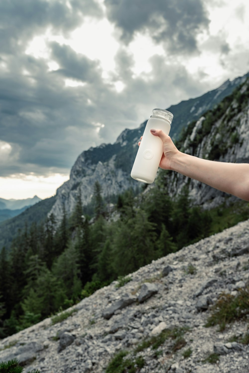 a man holding a bottle of water on top of a mountain