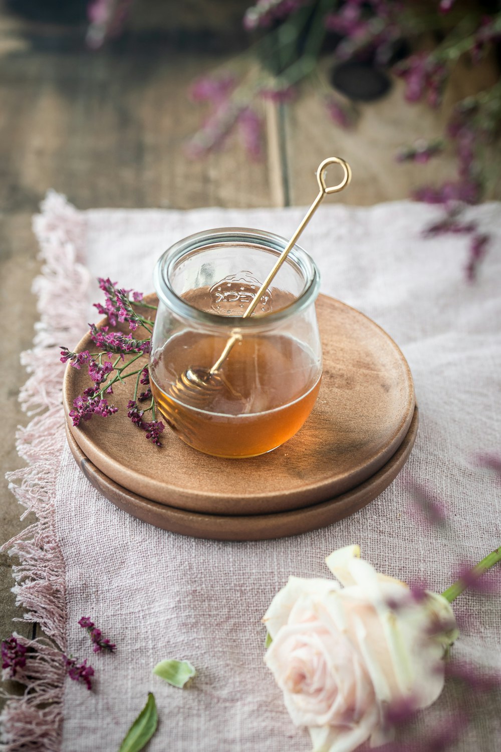 a jar of honey and a flower on a table
