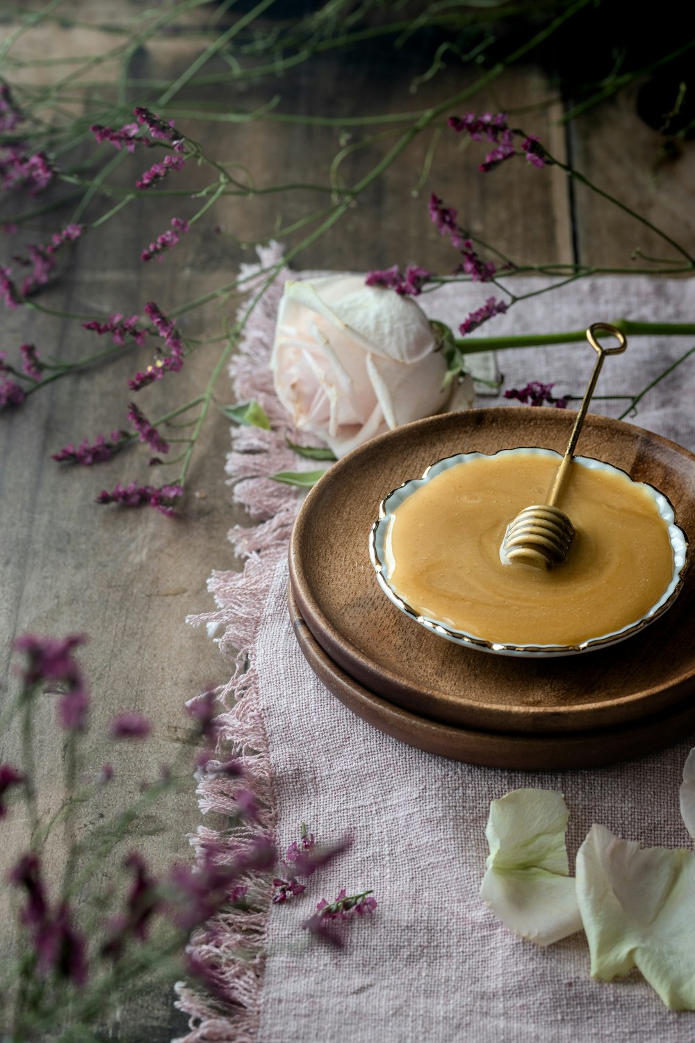 a plate with a honey dip on it next to flowers