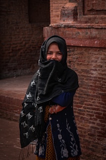 a woman in a black shawl and a brick building