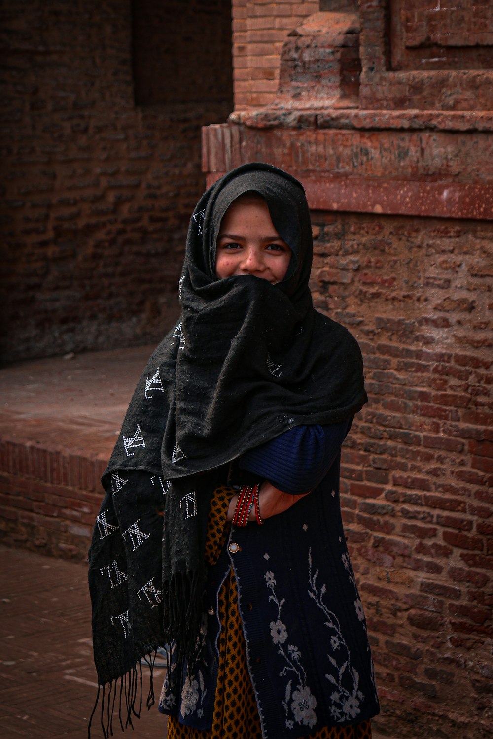 a woman in a black shawl and a brick building