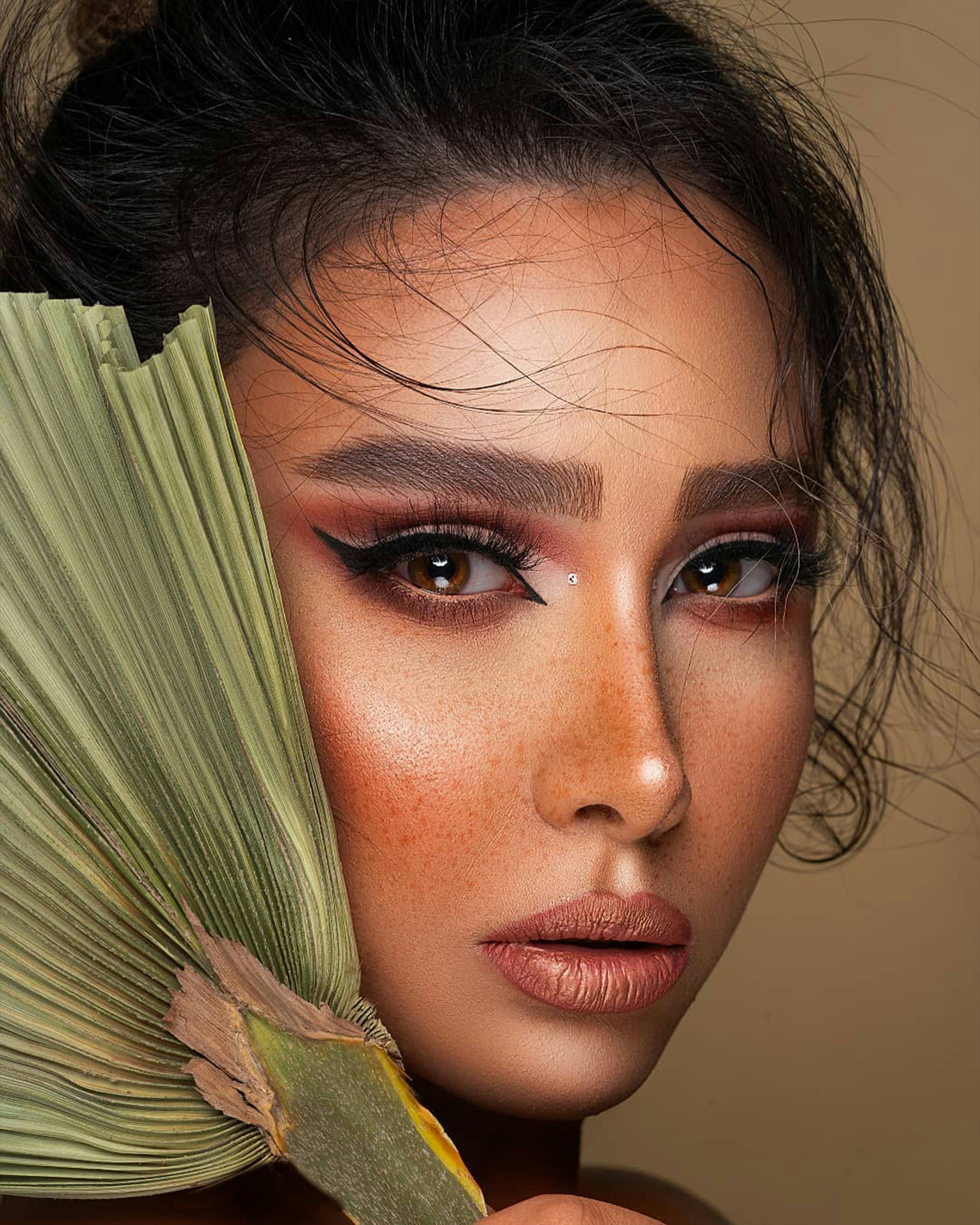 a woman holding a green leaf over her face
