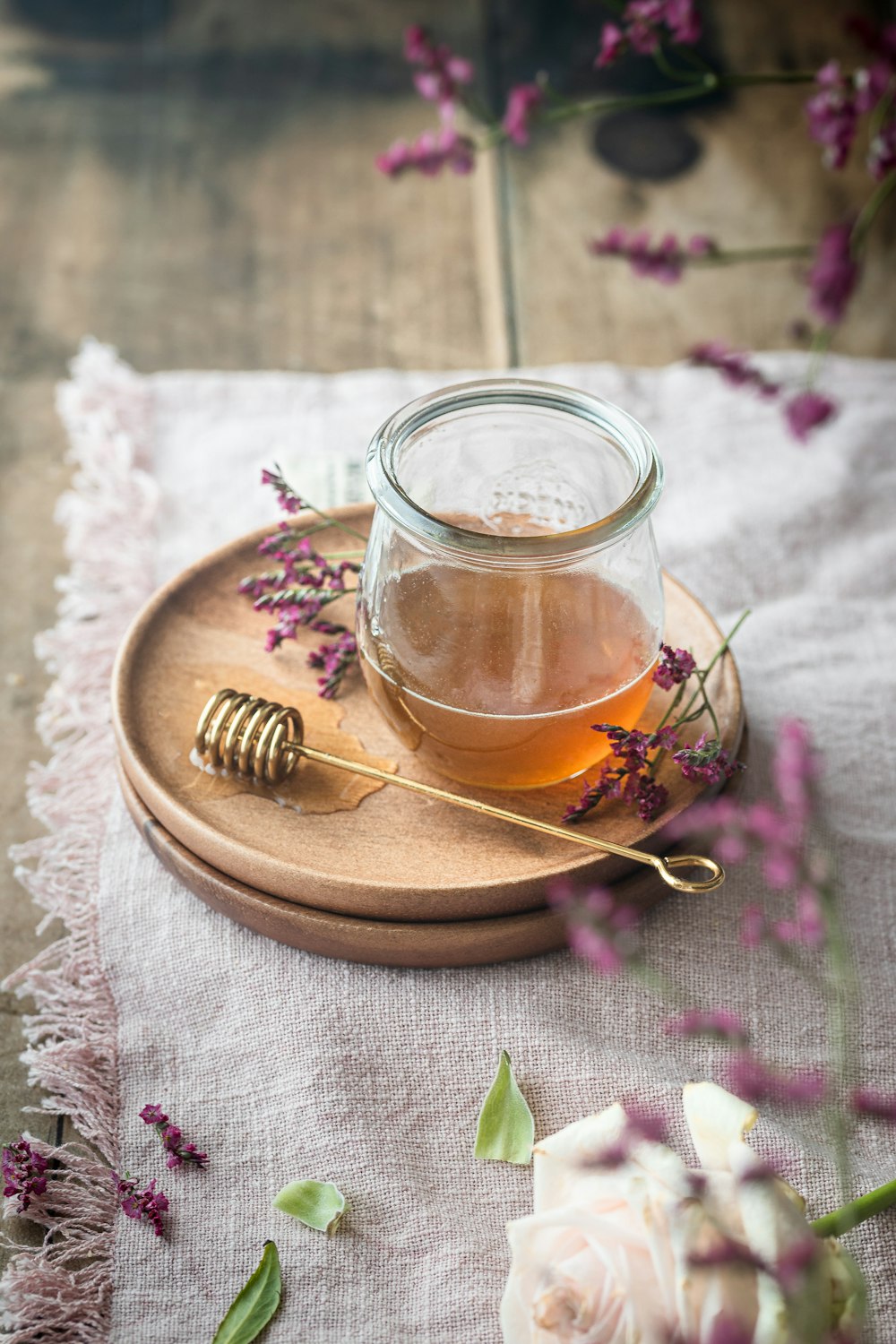 a jar of honey sits on a plate with flowers