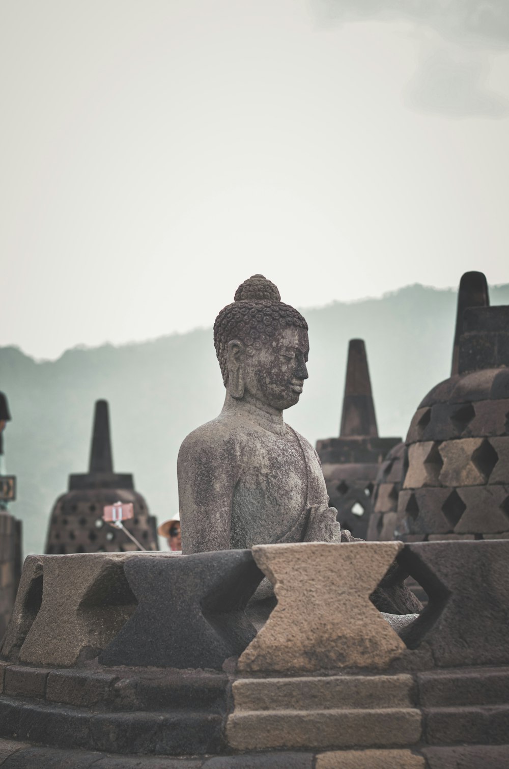 a statue of a person sitting in front of a mountain