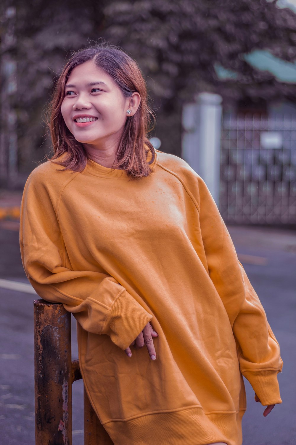 a woman standing next to a fence wearing a yellow sweatshirt