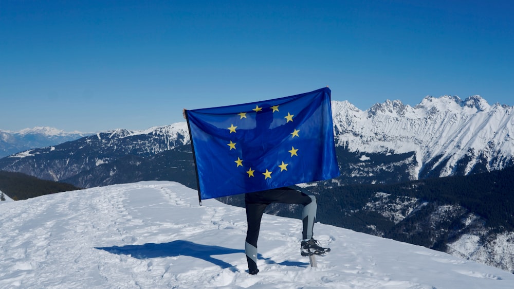 雪に覆われた山の頂上で旗を持つ男