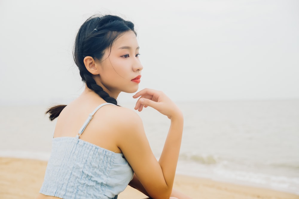 a woman sitting on a beach next to the ocean