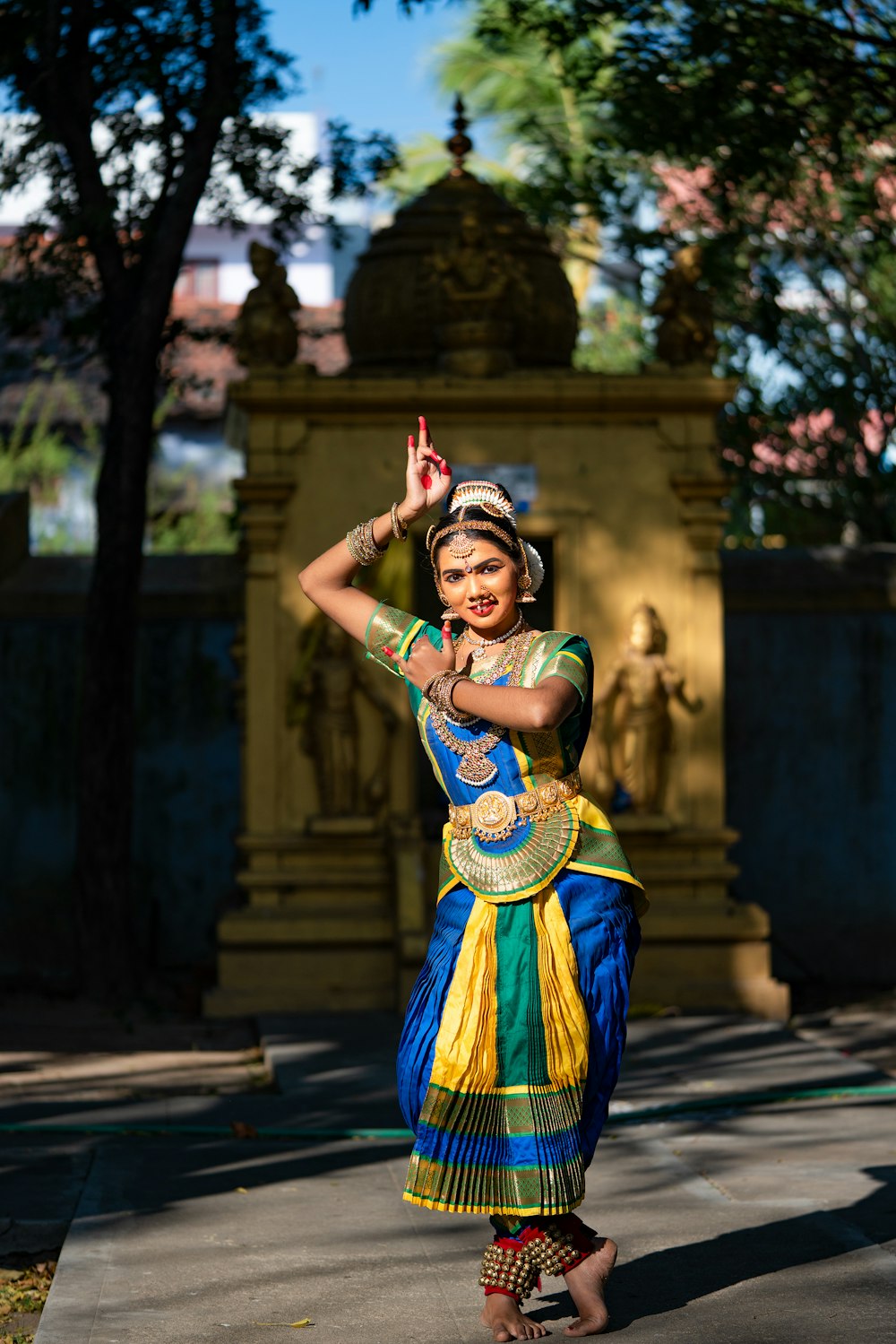 a woman in a colorful dress standing in front of a statue