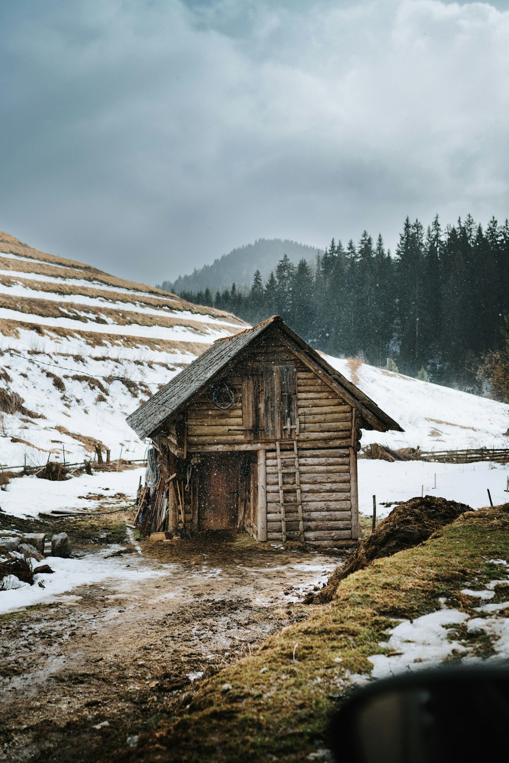 a small wooden shack sitting on top of a snow covered hillside