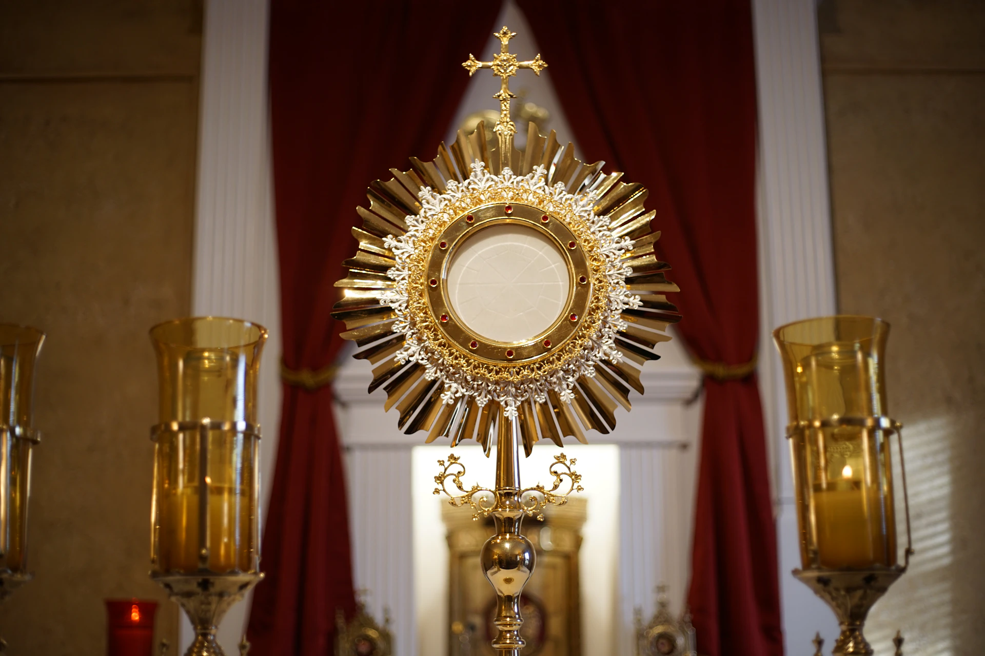 a golden cross and two candles in front of a window